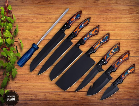 A set of handmade chef knives with black blades and wooden handles, accompanied by a leather sheath roll, displayed on a wooden surface.