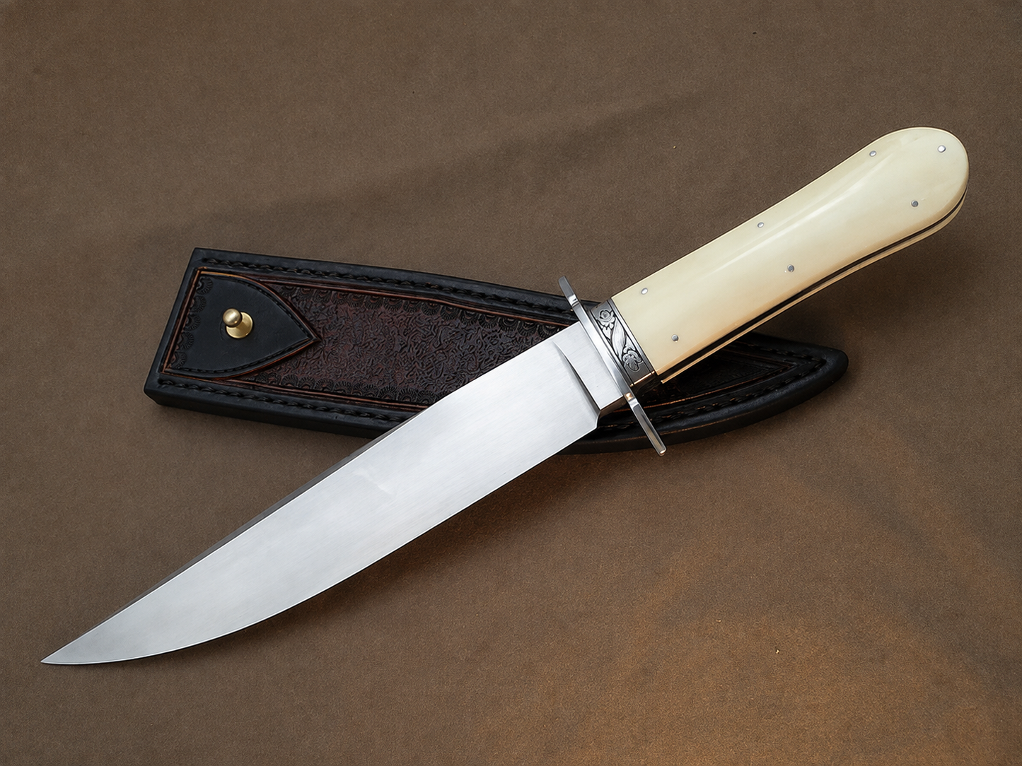 A fixed-blade knife with a polished silver blade and a cream-colored bone handle, resting diagonally on its dark brown leather sheath against a textured brown background.