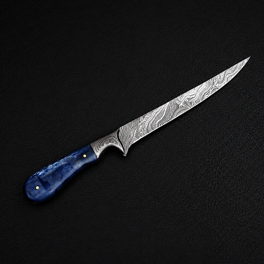 A Damascus steel kitchen knife with a patterned silver blade and a textured blue handle, displayed diagonally on a dark textured background.