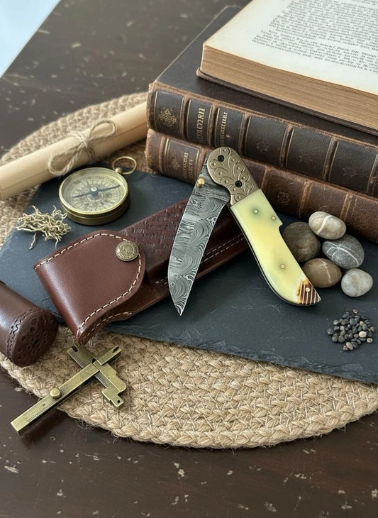 Vintage-style knife, compass, and books on a textured surface