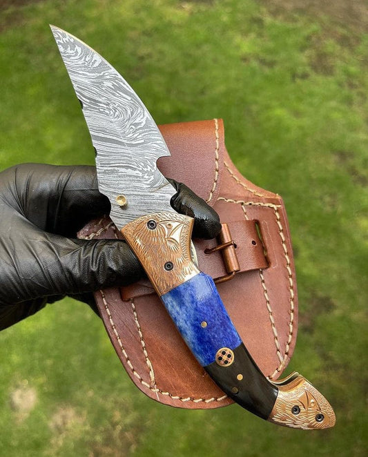 Decorative knife with a blue blade and wooden handle held by a gloved hand against a green background