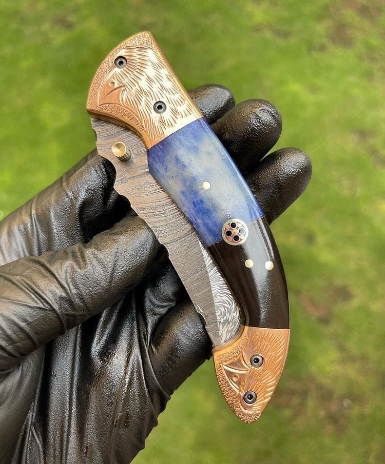 Handheld knife with decorative wooden handle and blue blade against a green background
