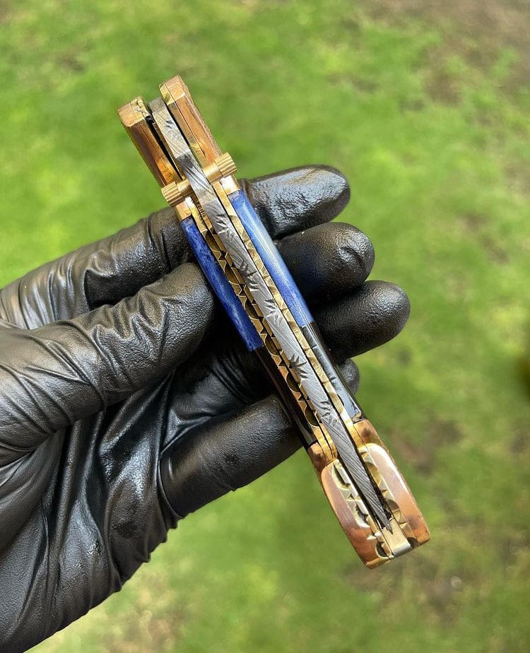 Metallic pen held by a gloved hand against a green background