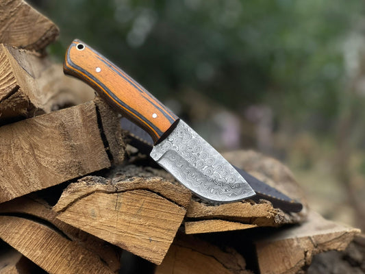 Knife with a wooden handle on stacked wood logs outdoors