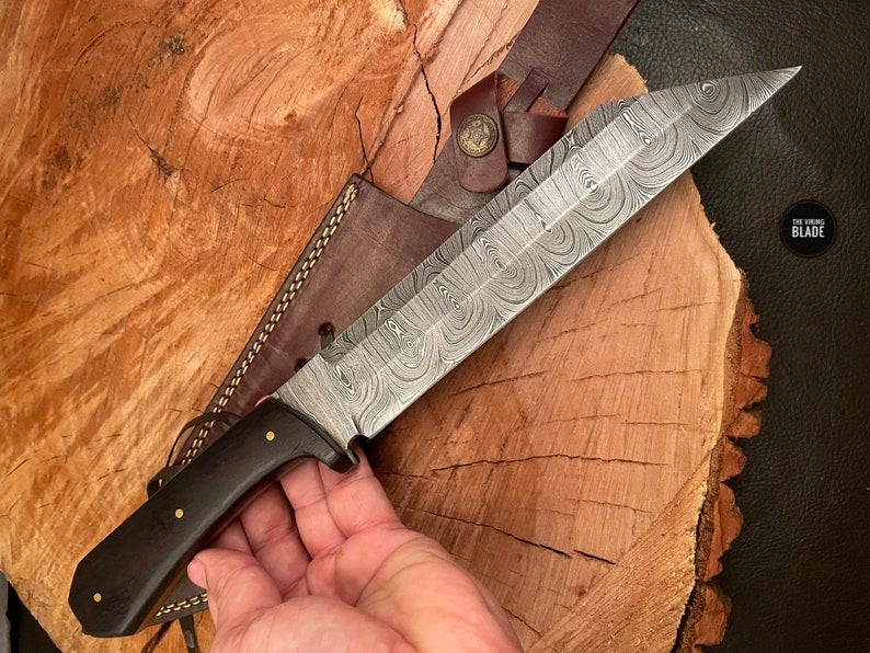 Damascus steel Seax knife with wooden handle and leather sheath ready for everyday carry.