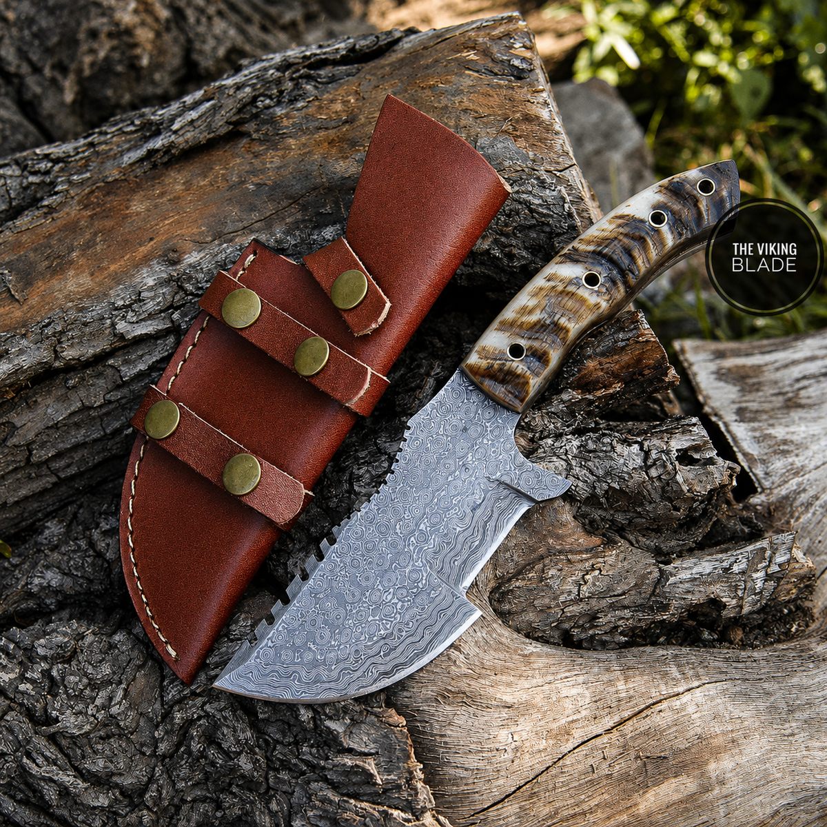 A fixed-blade knife with a patterned steel blade and a carved handle, shown resting on a log next to a brown leather sheath. A circular logo in the upper right reads 'THE VIKING BLADE'.