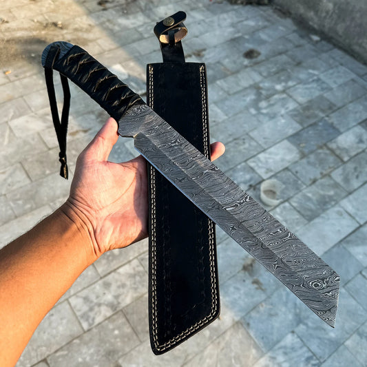 Hand holding a large Damascus steel sword with a black sheath on a stone pavement background