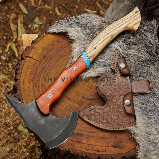 Wooden-handled axe with leather sheath on a wooden log and fur background, featuring 'The Viking Axe' branding.