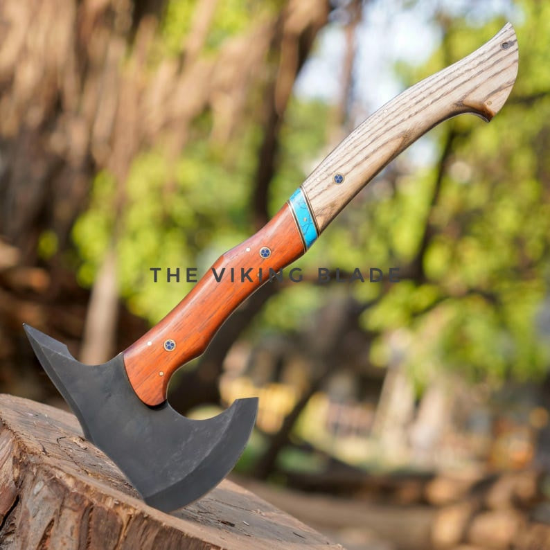 Axes with wooden handles on a tree stump against a blurred natural background
