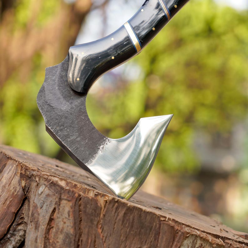 Decorative axe with a black handle on a wooden log against a blurred natural background