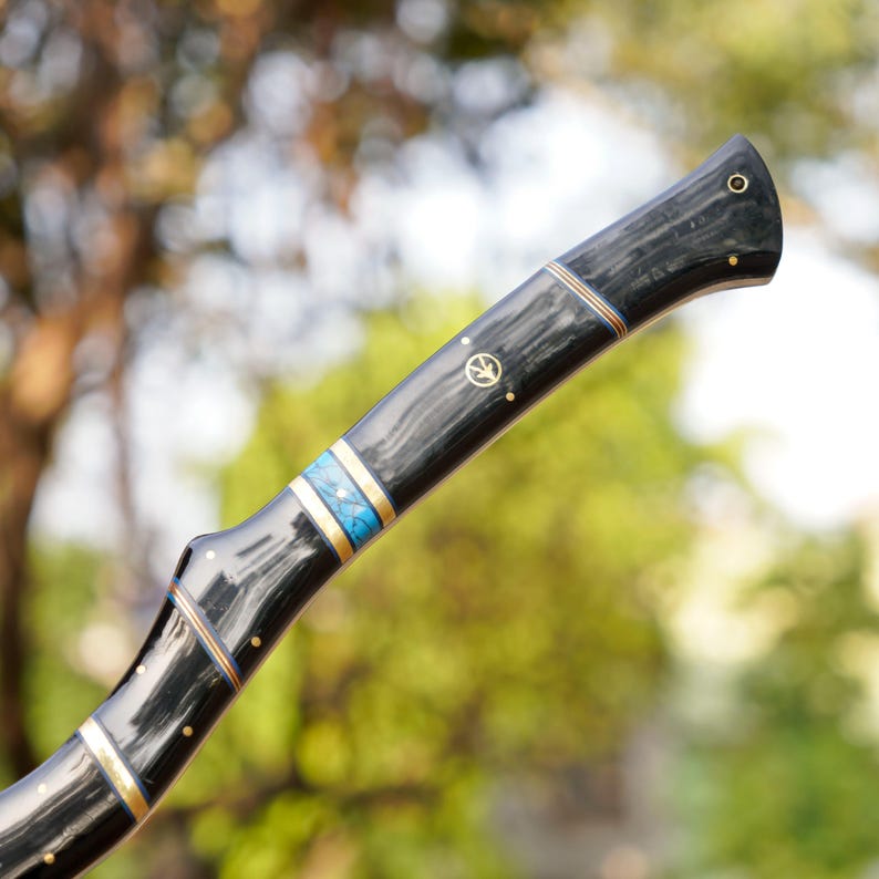 Black-handled tool with decorative elements against a blurred natural background