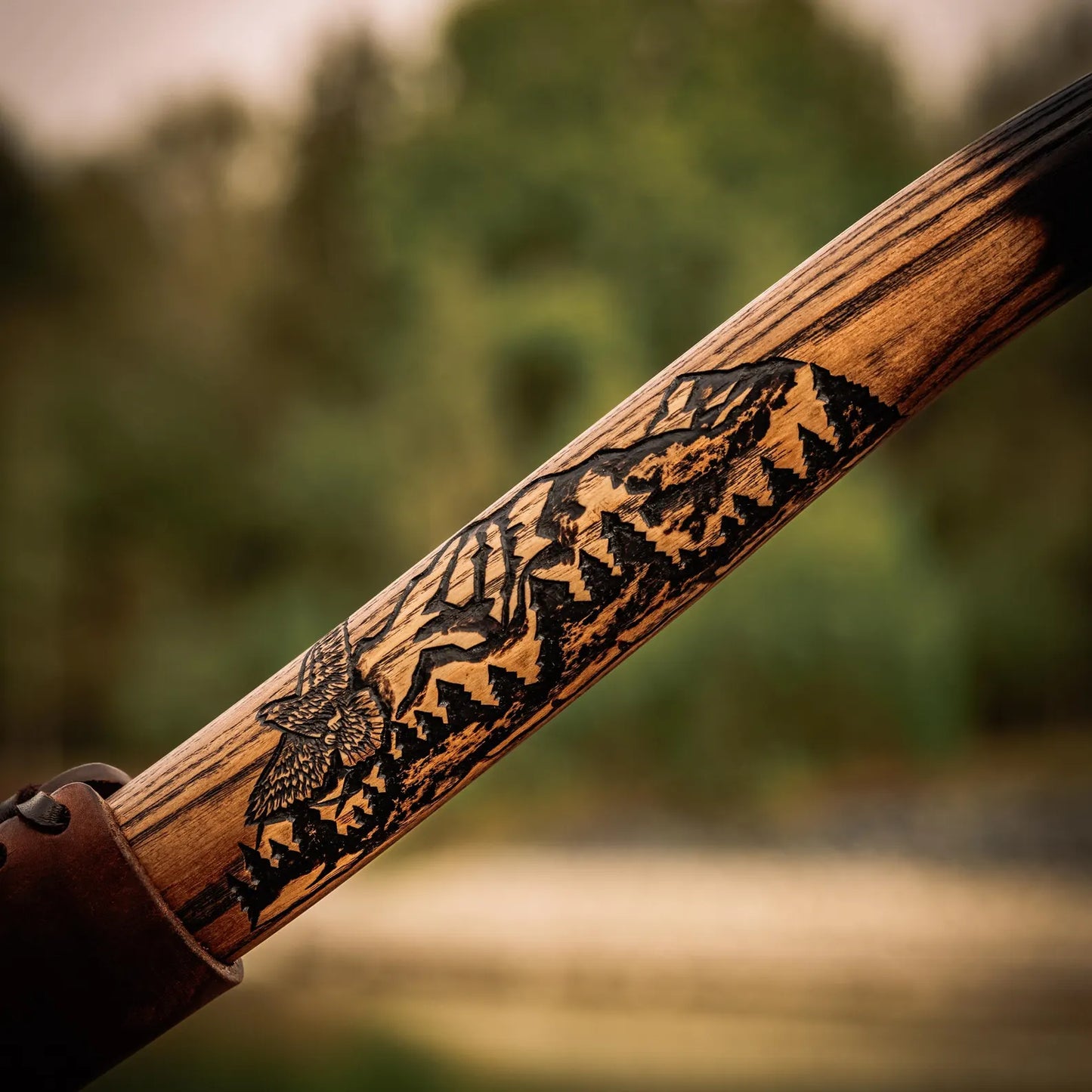 Wooden handle with engraved design against a blurred natural background