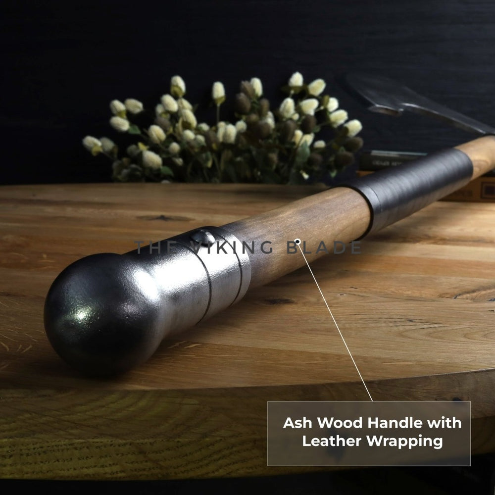 Wooden handle with leather wrapping on a wooden surface, branded 'The Viking Blade'.