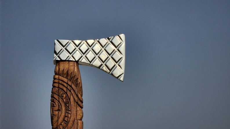 Wooden axe head with a silver axe blade on a blue background