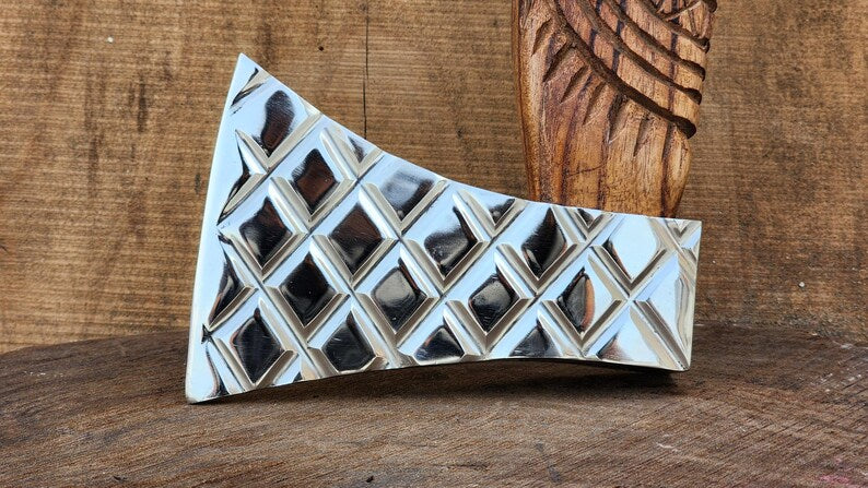 Decorative stone axe with geometric pattern on a wooden surface