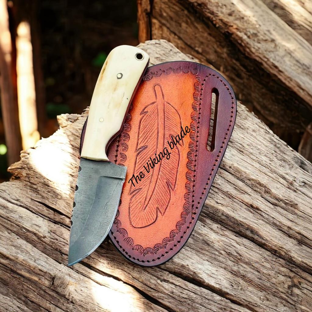 Knife with leather sheath on a wooden surface, featuring 'The Viking Blade' branding.