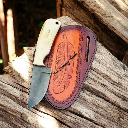 Knife with leather sheath on a wooden surface, featuring 'The Viking Blade' branding.