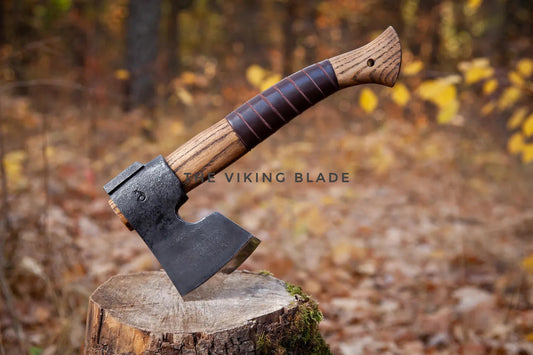 Axes with wooden handles on a stump in a forest setting, featuring 'The Viking Blade' branding.