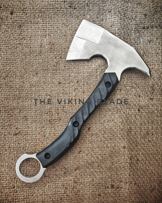Hand axe with a black handle on a textured brown background, branded 'The Viking Blade'.