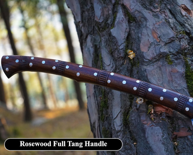 Rosewood full tang handle against a tree trunk with a blurred forest background