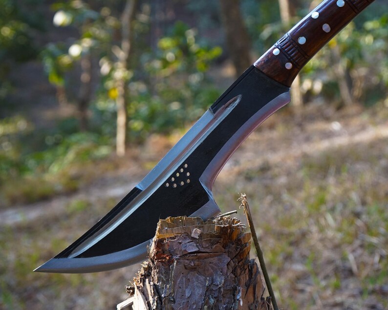 Tactical knife with wooden handle on a tree stump in a forest setting