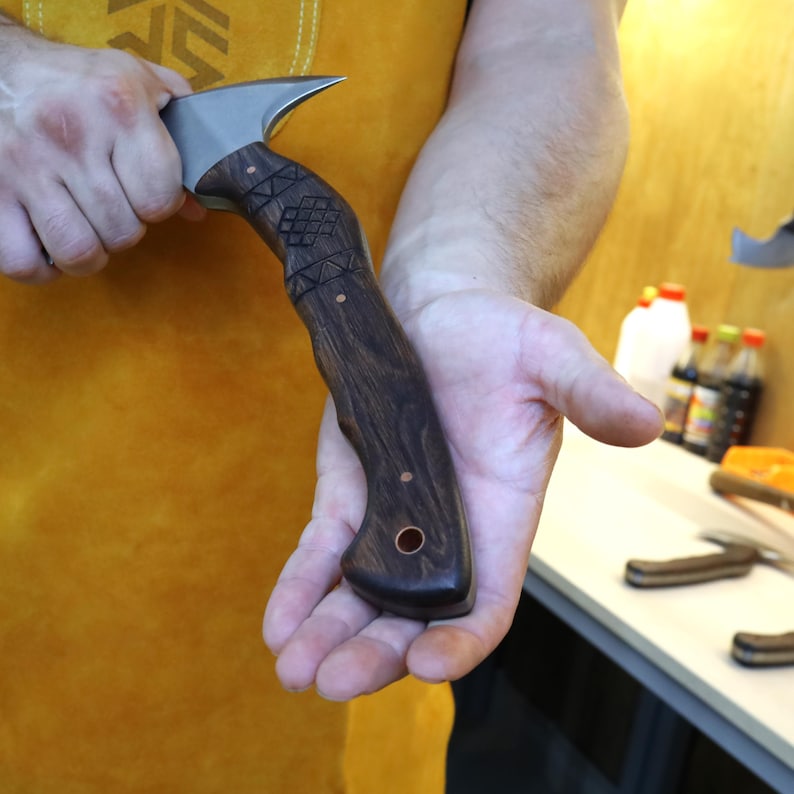 Hand holding a knife with a wooden handle against a blurred background