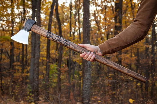Person holding a wooden-handled axe in a forest setting