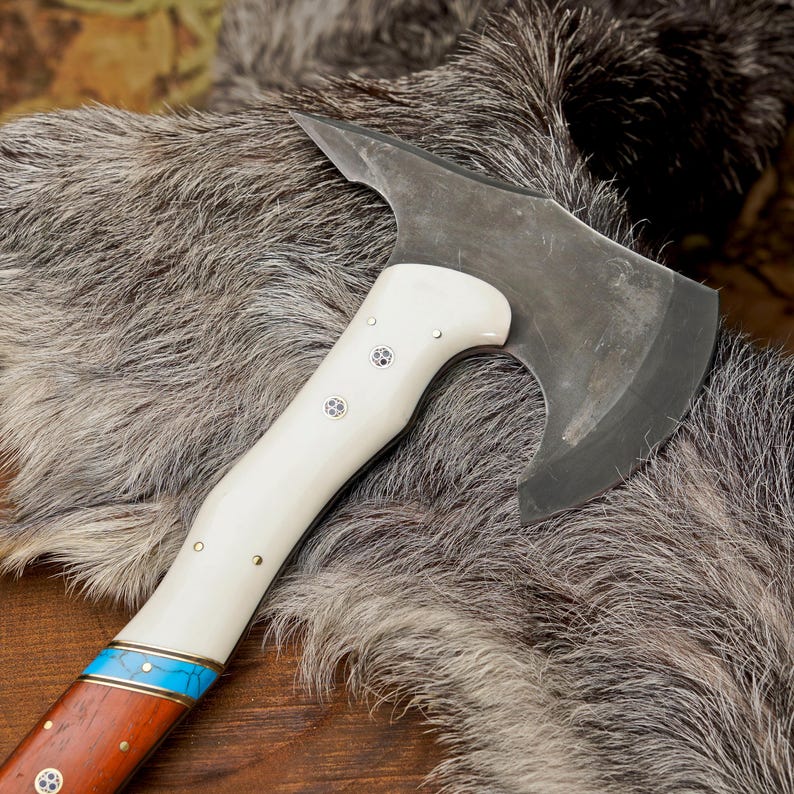 Axes with white and brown handles on a fur surface