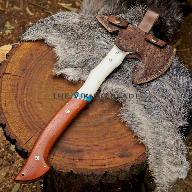 Wooden-handled axe with leather sheath on a wooden log