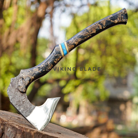 Decorative axe with a wooden handle on a tree stump, blurred greenery in the background