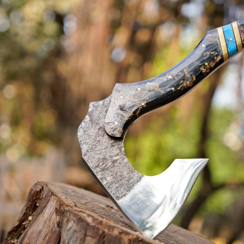 Close-up of a axe with a decorative handle on a blurred natural background