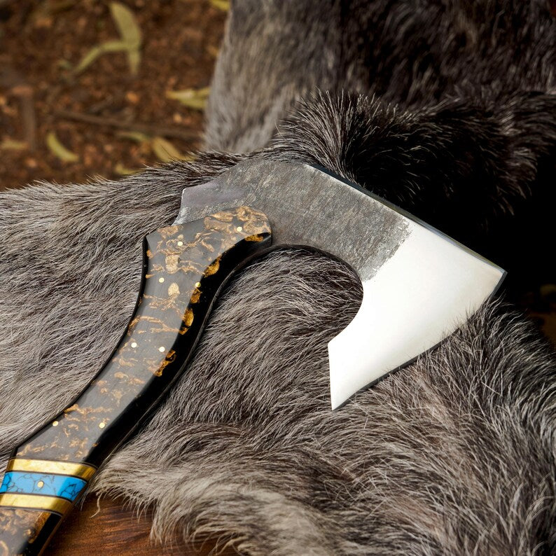 Close-up of a decorative axe with a wooden handle on a fur surface