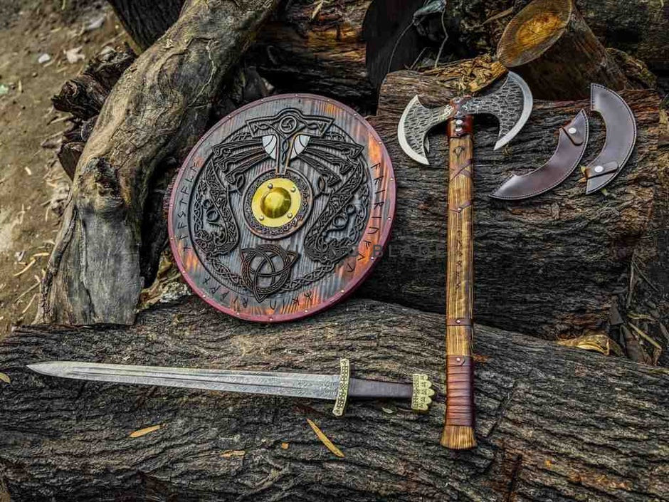 Viking-style sword, shield, and axe on a wooden surface