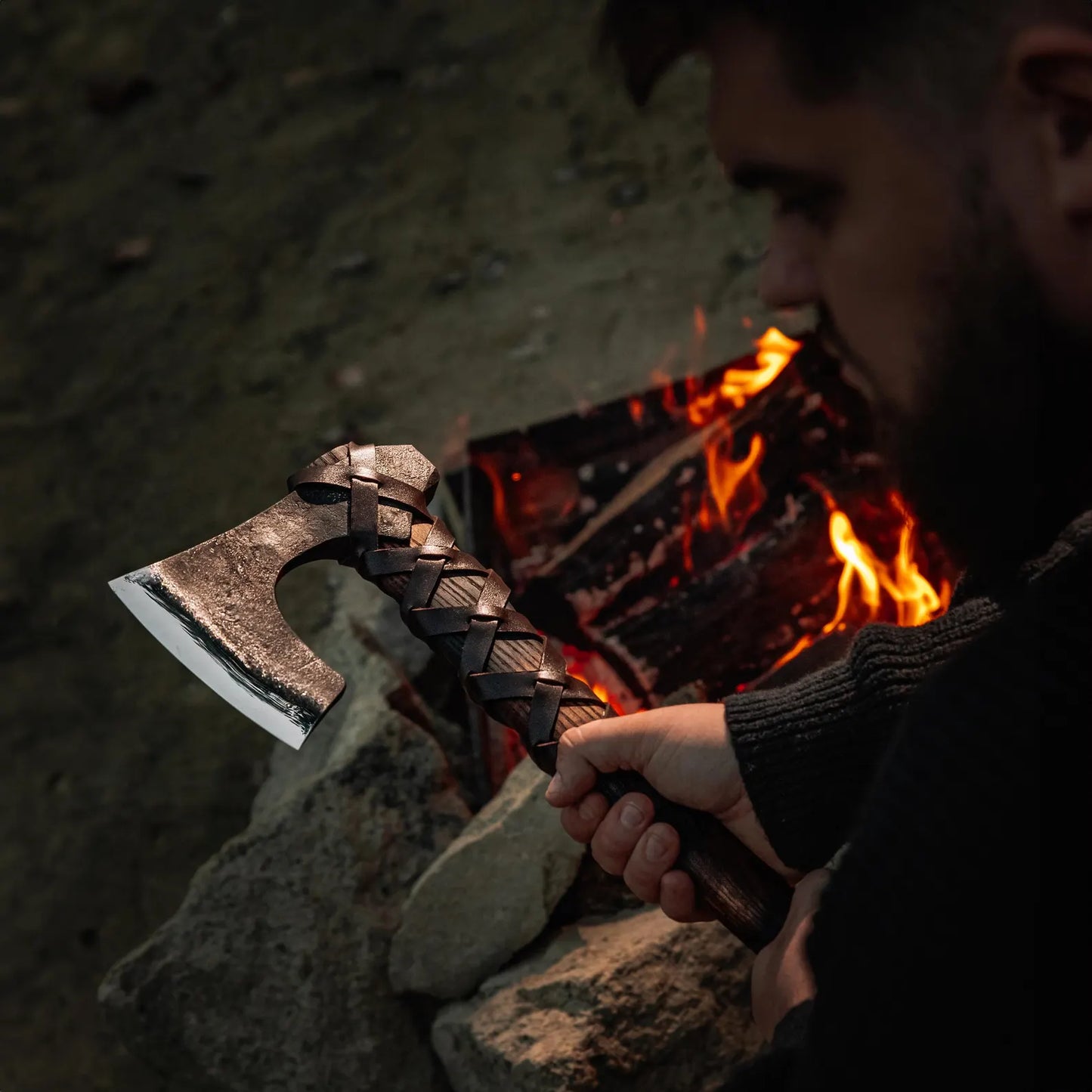 Person holding a axe by a campfire with a dark background