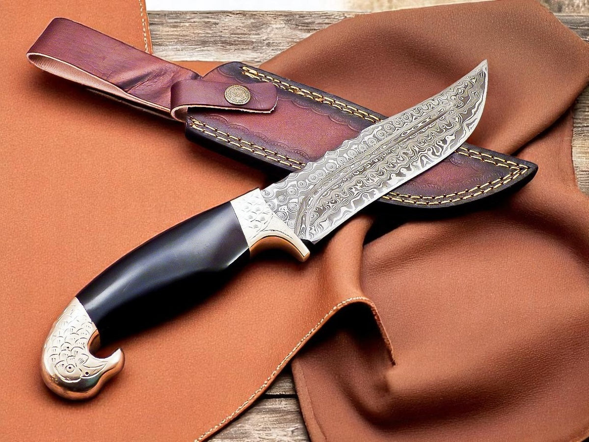Decorative knife with black handle and silver blade on brown leather background