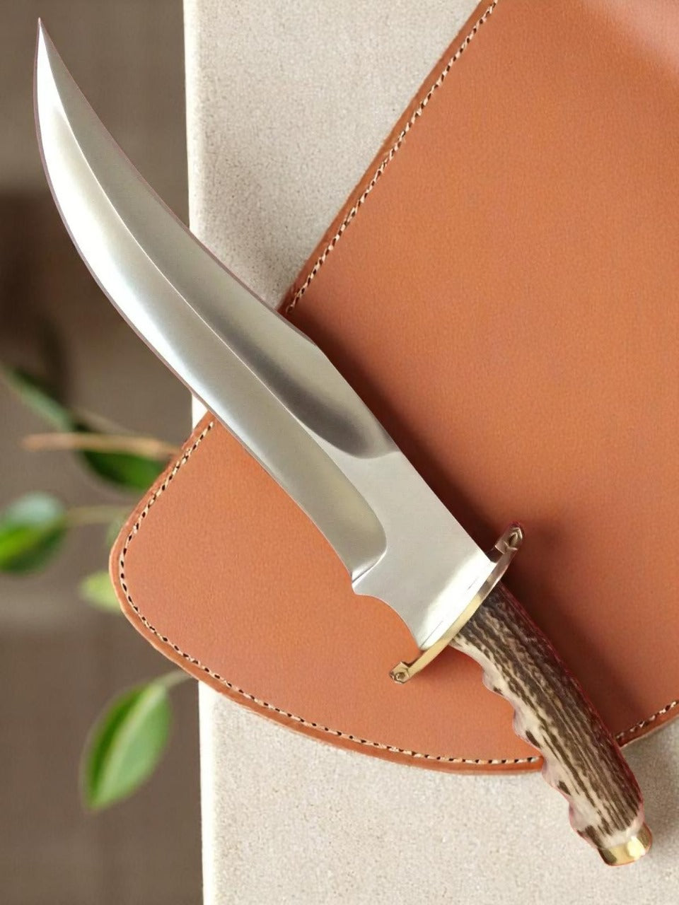 Knife with antler handle in leather sheath.