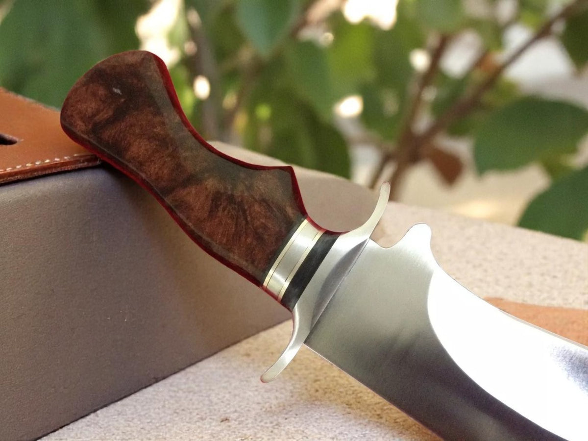 Close-up of a knife with a wooden handle partially sheathed.