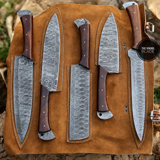 Five large kitchen knives with patterned steel blades and dark brown wooden handles are arranged on a tan leather knife roll outdoors on a stone surface. A circular badge reads 'THE VIKING BLADE'.
