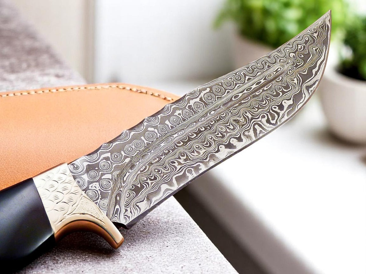 Decorative knife with patterned blade on a leather sheath.