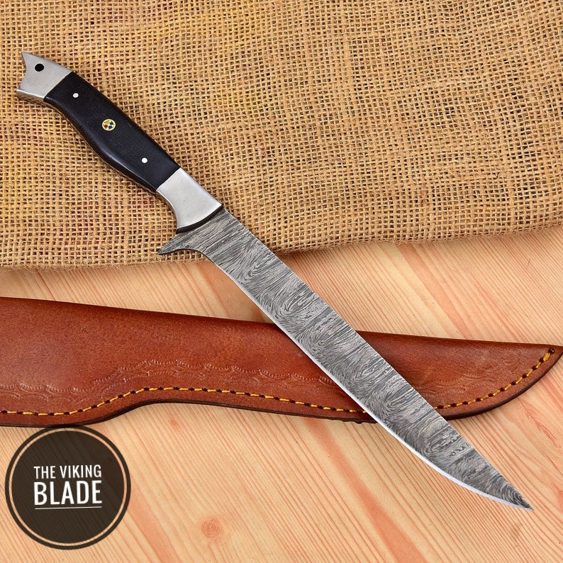 A custom handmade Damascus steel fillet fish chef knife with a black and silver striped blade and a brown leather sheath.