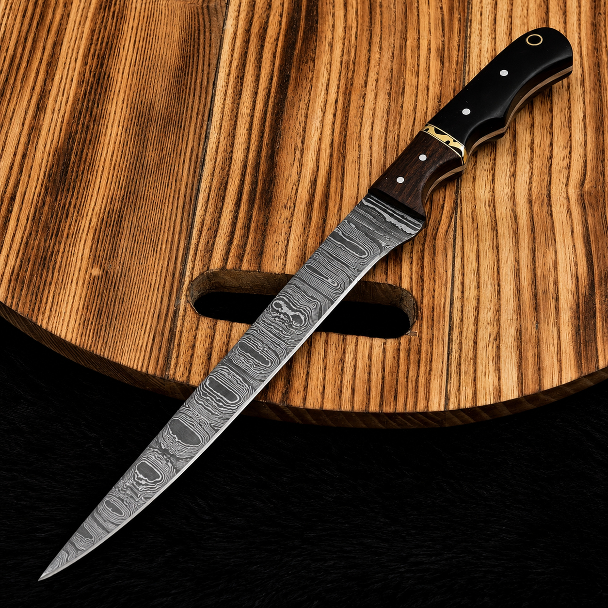 A Damascus steel utility knife with a patterned blade, dark wood handle, and brass bolster, resting diagonally on a wooden cutting board.