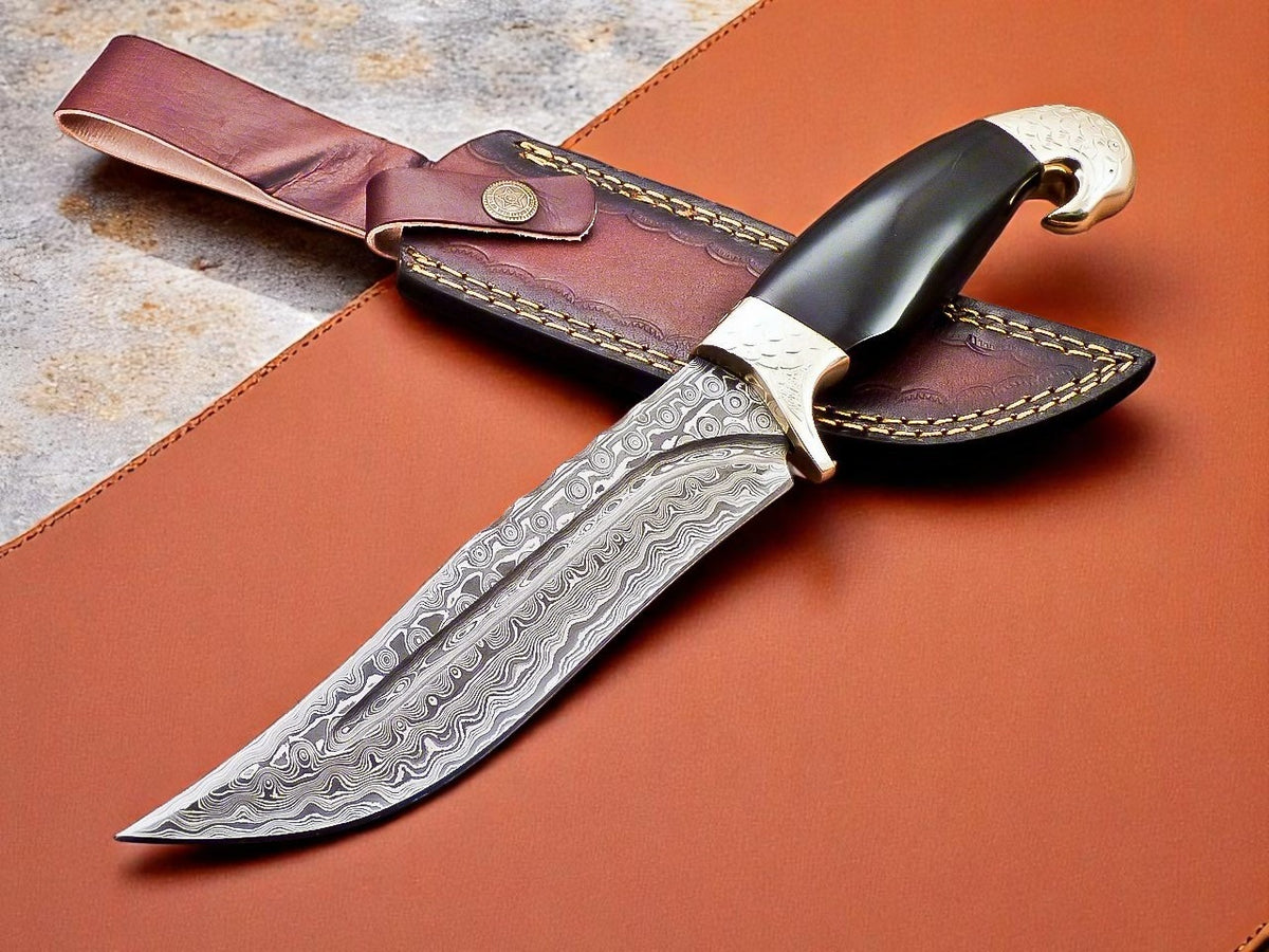 A custom handmade Damascus steel hunting knife with a brown leather sheath. The knife features a patterned blade, a black and brown handle with brass bolsters, and a silver metal guard.