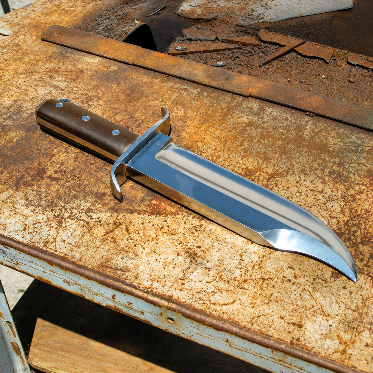 A fixed-blade knife with a polished silver steel blade and a brown wooden handle, resting diagonally on a heavily rusted metal workbench.