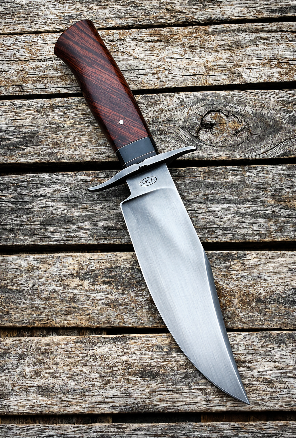 A fixed-blade knife with a polished silver steel blade and a reddish-brown wood handle, displayed diagonally on a rustic weathered wooden plank surface.