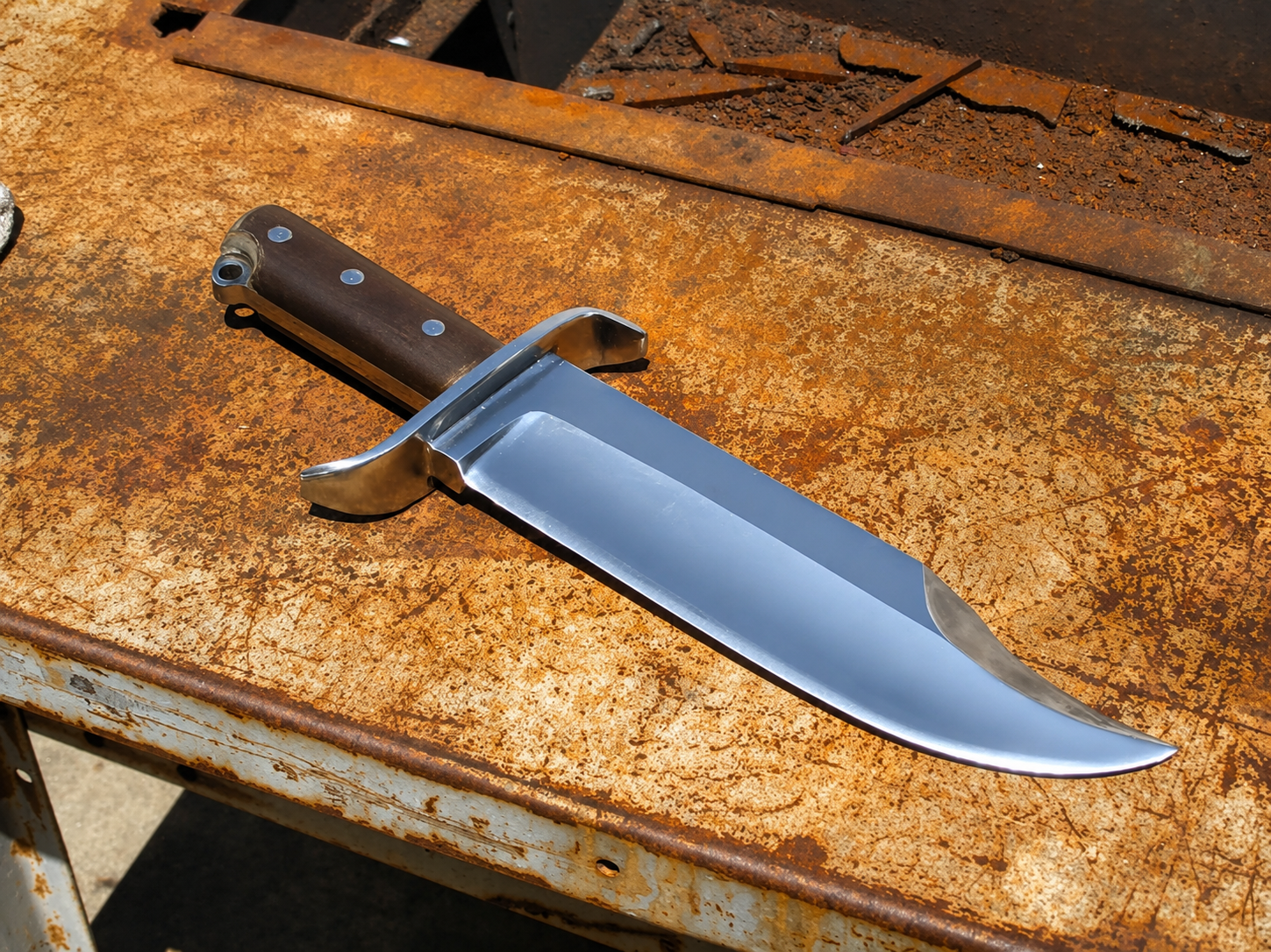 A fixed-blade knife with a polished silver blade and a brown wooden handle, resting diagonally on a heavily rusted metal workbench.