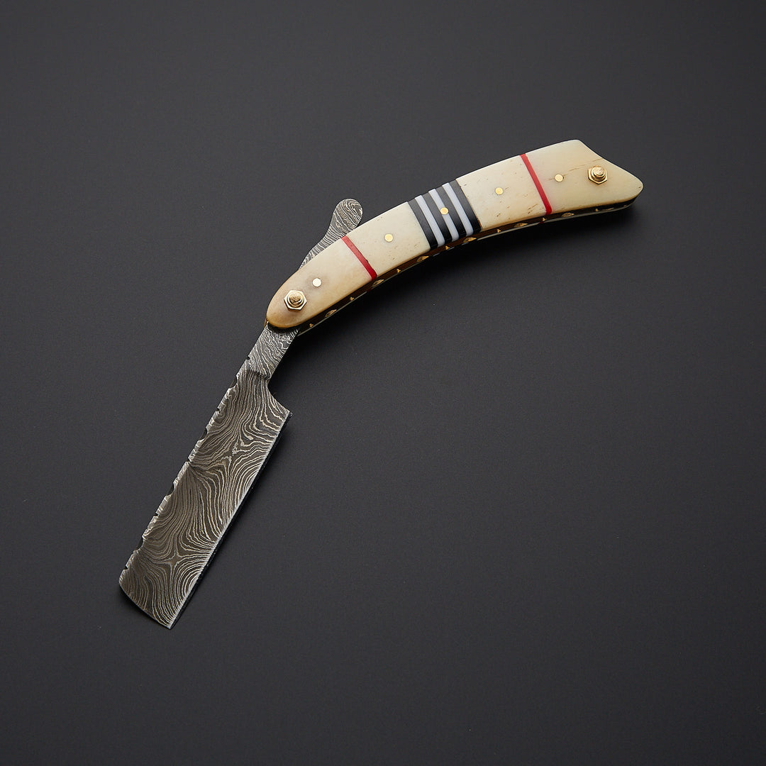 artisan Damascus steel straight razor blade showing unique layered pattern and razor-sharp cutting edge.