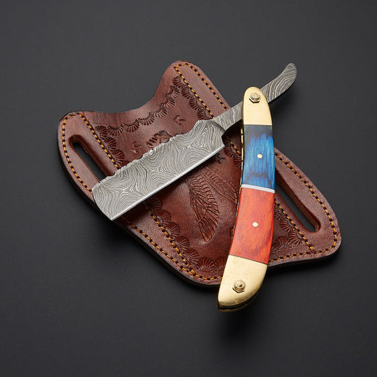 A straight razor with a Damascus steel blade and a colorful wood handle, displayed diagonally on top of its brown embossed leather sheath against a dark gray background.