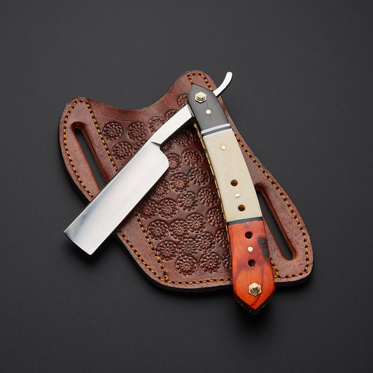 A folding pocket knife with a polished steel blade and a carved wooden handle rests on a brown leather sheath with embossed floral detailing, set against a dark gray background.