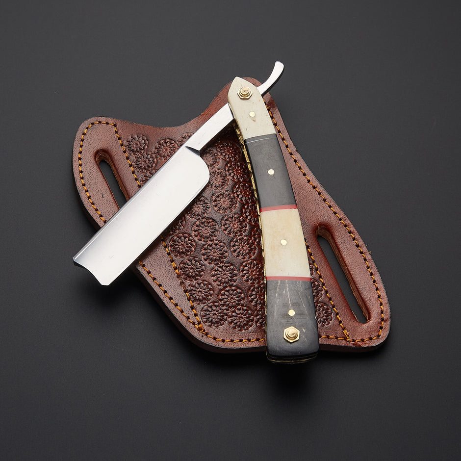 A straight razor with a dark wood and bone handle, displayed diagonally on its brown leather sheath against a dark gray background.