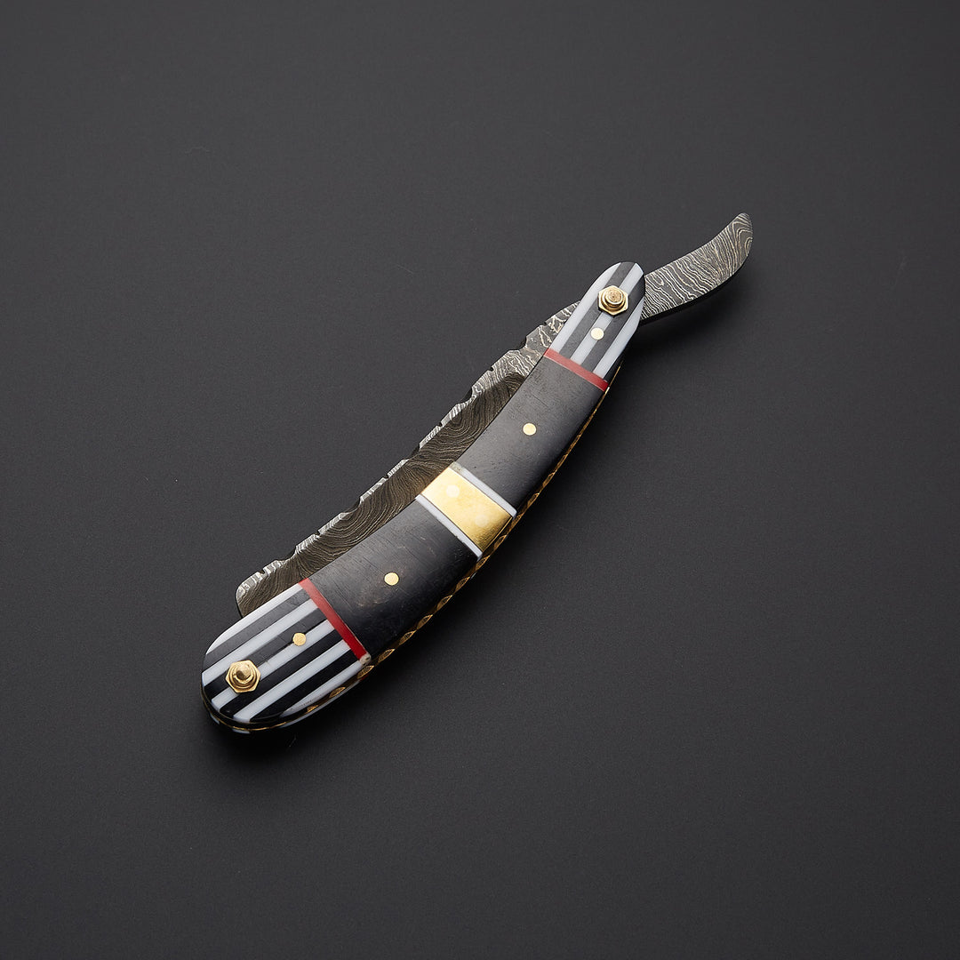 Detailed close-up of Damascus steel razor blade highlighting unique layered texture and precision honed shaving edge.